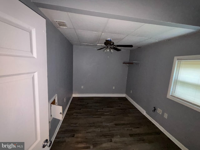 interior space with ceiling fan, visible vents, baseboards, dark wood-style floors, and a drop ceiling