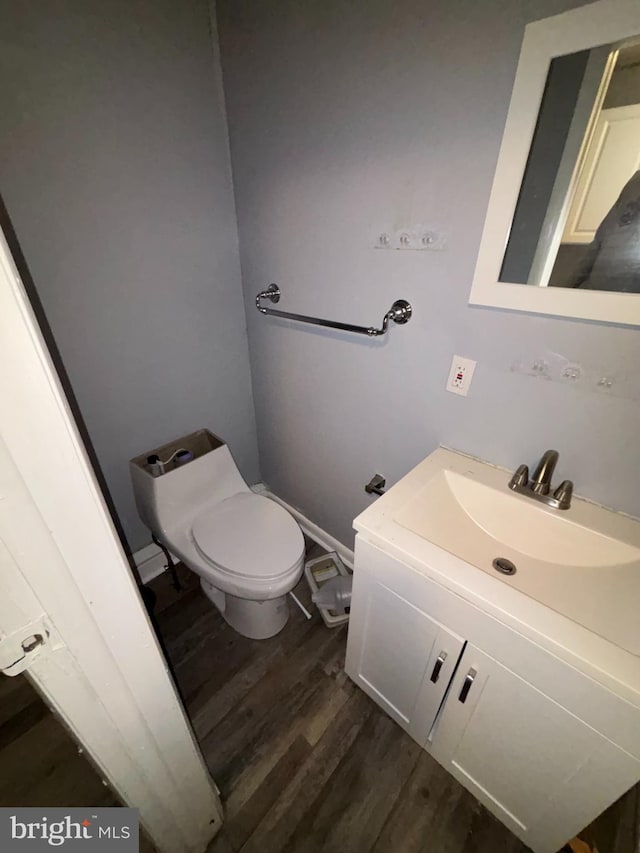 half bath featuring vanity, wood finished floors, and toilet