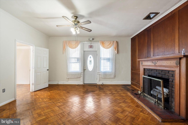 interior space with baseboards, a ceiling fan, a brick fireplace, and crown molding