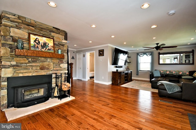 living room featuring wood finished floors, ornamental molding, ceiling fan, baseboards, and visible vents