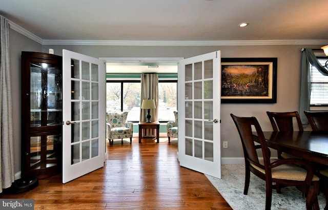 interior space with baseboards, wood finished floors, ornamental molding, and french doors