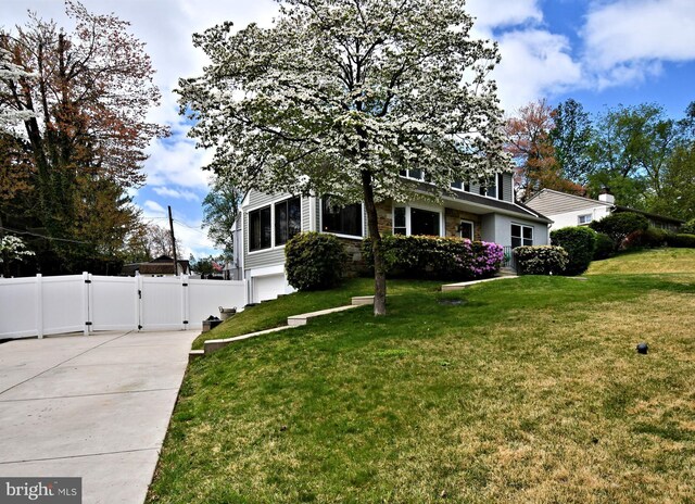 obstructed view of property with a front yard, fence, a garage, and a gate