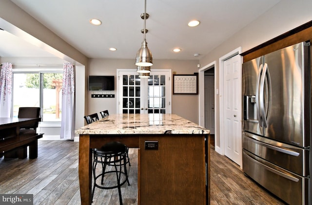 kitchen featuring dark wood-type flooring, a breakfast bar area, french doors, and stainless steel fridge with ice dispenser