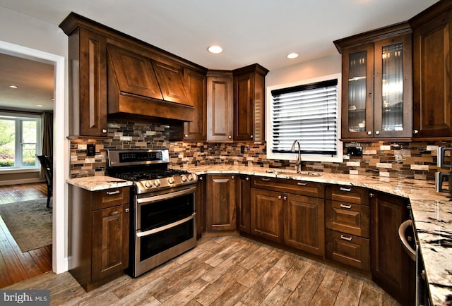 kitchen featuring double oven range, a sink, dark brown cabinetry, and wood finished floors