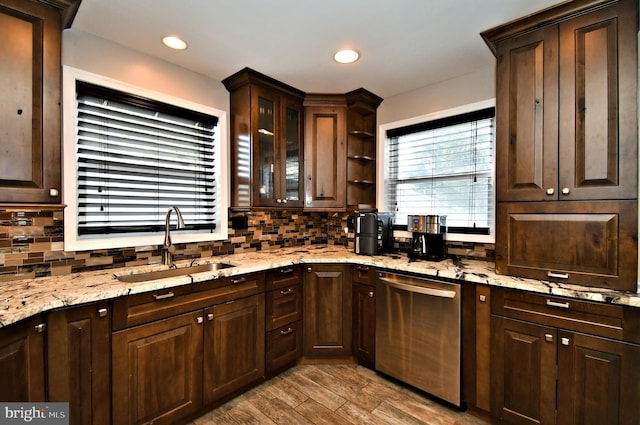 kitchen with dark brown cabinets, stainless steel dishwasher, decorative backsplash, and a sink