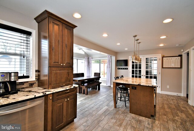 kitchen featuring light stone counters, a breakfast bar, baseboards, recessed lighting, and dark wood finished floors