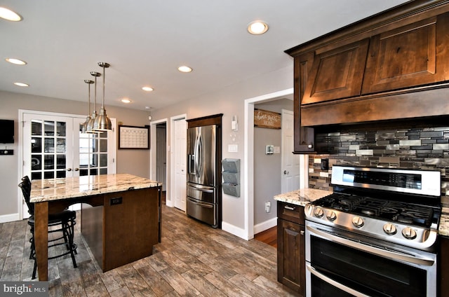 kitchen featuring appliances with stainless steel finishes, a center island, a breakfast bar, baseboards, and dark brown cabinets