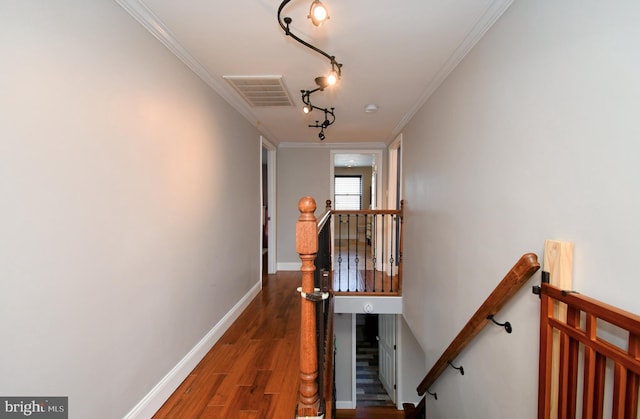 hallway with an upstairs landing, visible vents, baseboards, ornamental molding, and wood finished floors