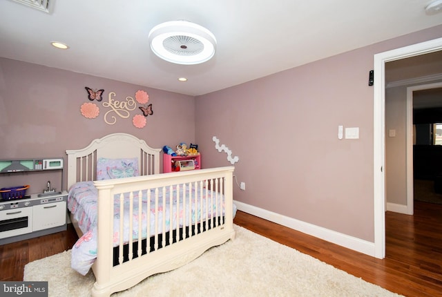 bedroom with wood finished floors, visible vents, recessed lighting, and baseboards