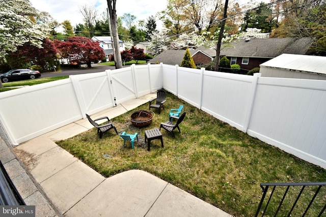 view of yard with a gate, an outdoor fire pit, and a fenced backyard