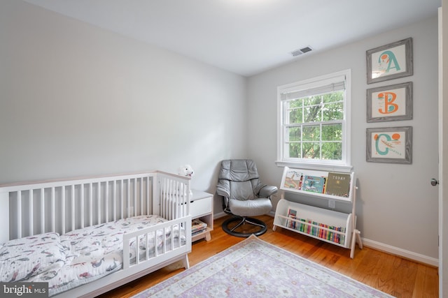 403 Thomas St, Alexandria, VA 22302 - bedroom with baseboards, a crib, wood finished floors, and visible vents