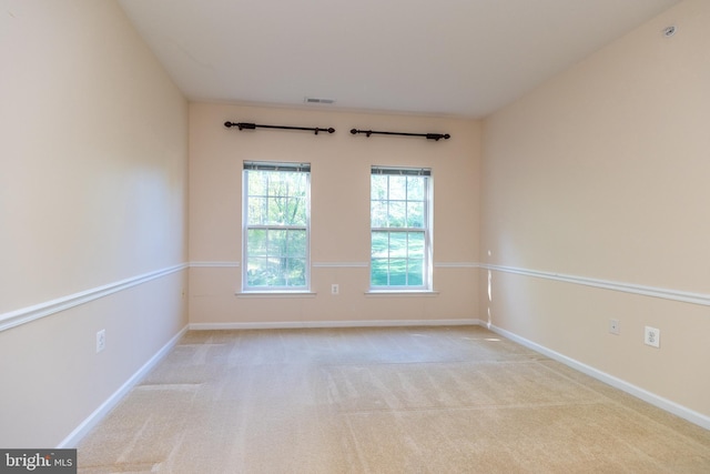 carpeted spare room featuring baseboards and visible vents