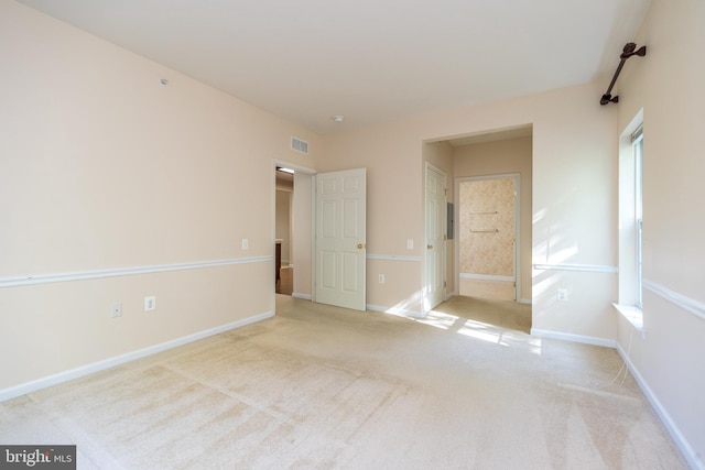 unfurnished bedroom with baseboards, ensuite bathroom, carpet flooring, and visible vents