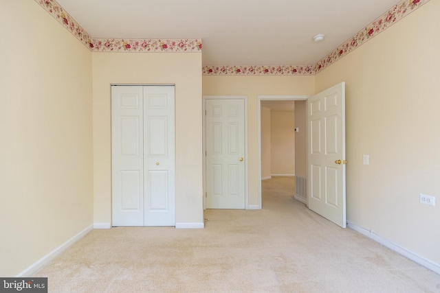 unfurnished bedroom with baseboards, light carpet, and a closet