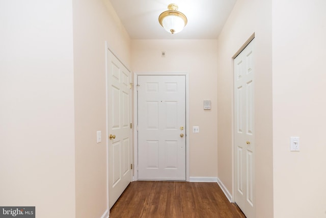 hall featuring baseboards and dark wood-type flooring