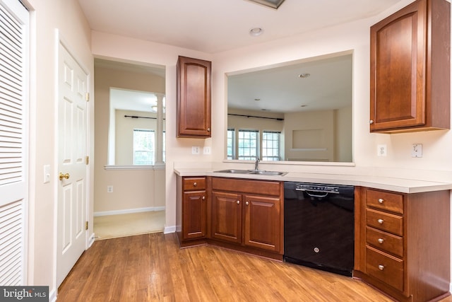 kitchen featuring brown cabinetry, light wood-type flooring, a sink, light countertops, and black dishwasher