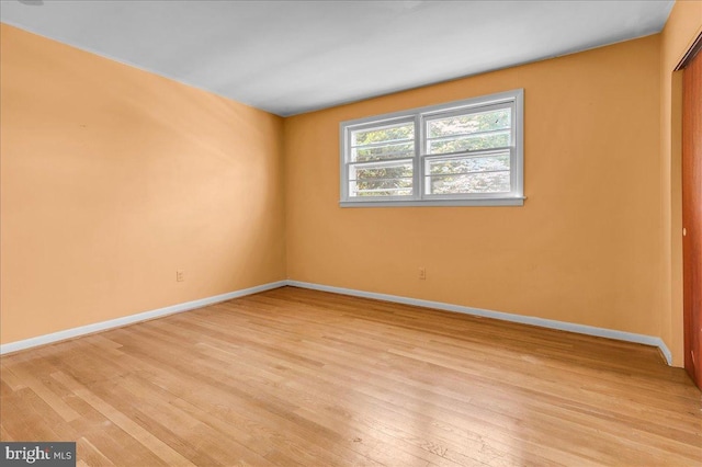 unfurnished bedroom with a closet, baseboards, and light wood-type flooring