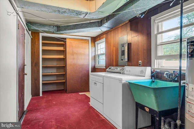 laundry room featuring gas water heater, electric panel, wooden walls, washer and dryer, and laundry area