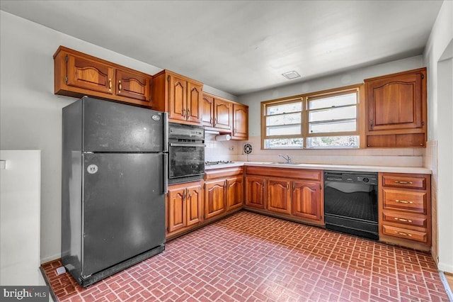 kitchen with black appliances, brown cabinets, brick patterned floor, and light countertops