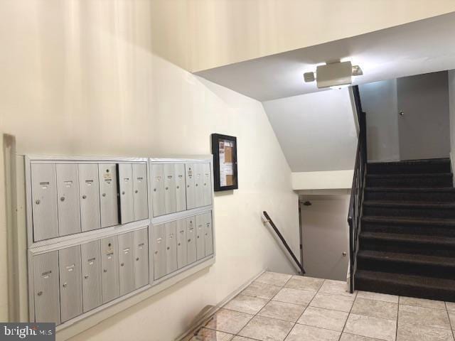 stairway with mail area, tile patterned flooring, and vaulted ceiling
