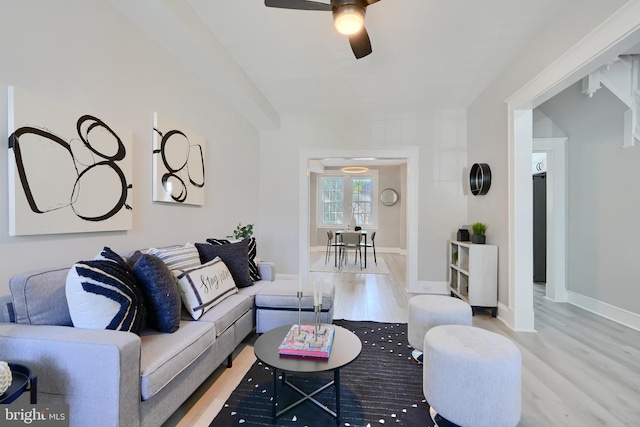 living area with light wood-type flooring, a ceiling fan, and baseboards