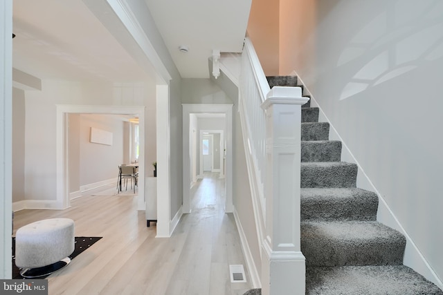 stairway with baseboards, wood finished floors, and visible vents