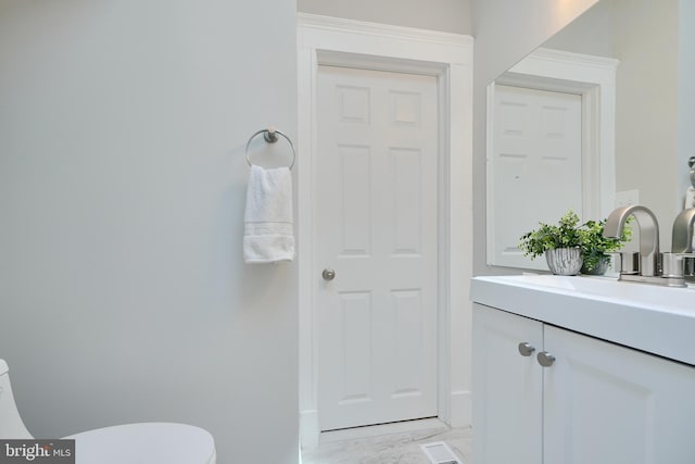 bathroom featuring toilet, baseboards, marble finish floor, and vanity