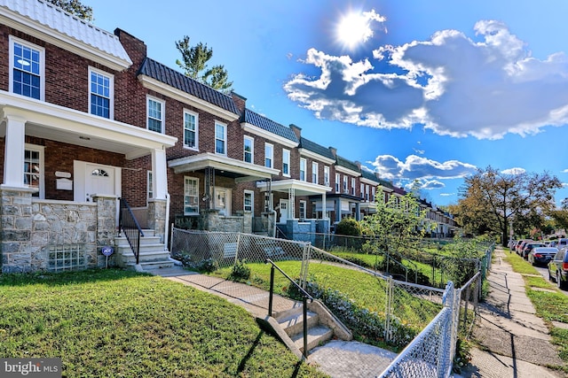 view of front facade featuring a residential view, fence, a front lawn, brick siding, and a tiled roof