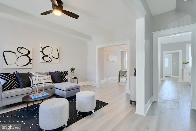 living room featuring a ceiling fan, baseboards, and light wood-type flooring
