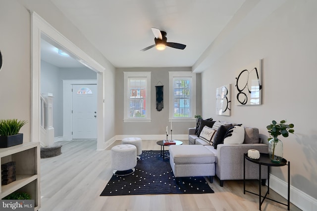 living room featuring baseboards, a ceiling fan, and wood finished floors