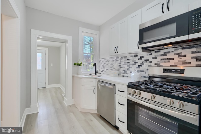 kitchen featuring a sink, light countertops, stainless steel appliances, white cabinetry, and decorative backsplash