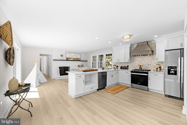 kitchen featuring premium range hood, stainless steel appliances, light wood finished floors, and white cabinetry