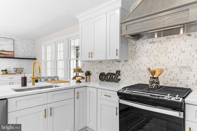 kitchen with a sink, wall chimney exhaust hood, backsplash, and gas range