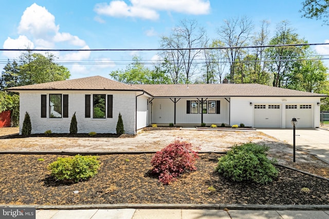 ranch-style house featuring a shingled roof, an attached garage, concrete driveway, and stone siding
