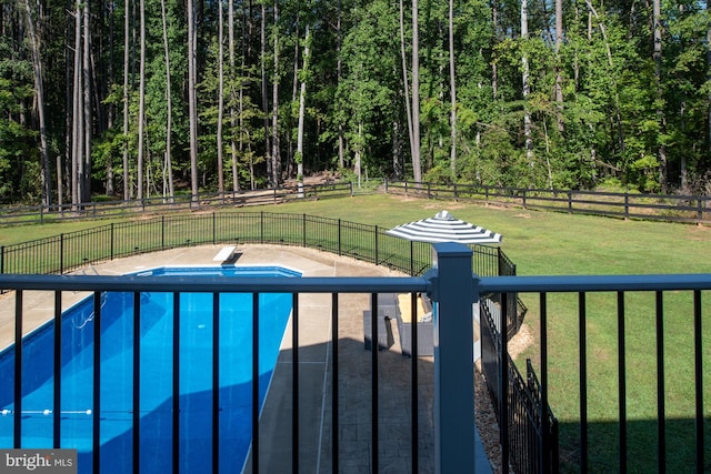 view of pool with a diving board and a wooded view