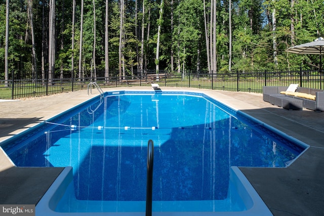 view of pool with a diving board, a patio area, fence, and a view of trees
