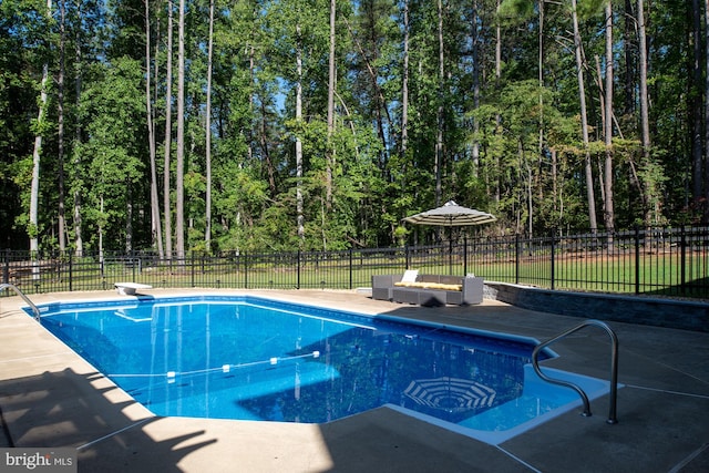 view of swimming pool with a diving board, fence, and a patio area