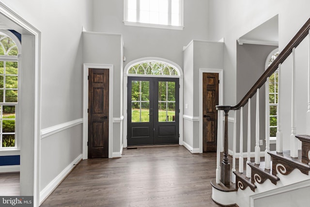 entryway featuring stairway, french doors, wood finished floors, and a high ceiling