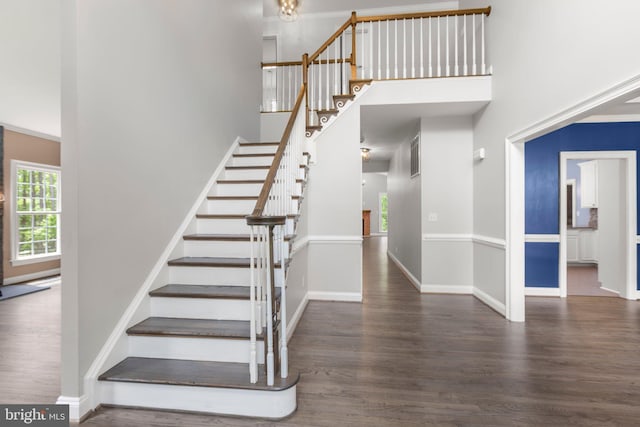 staircase with a high ceiling, wood finished floors, and baseboards