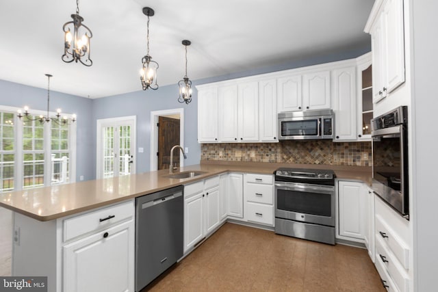 kitchen with stainless steel appliances, a peninsula, a sink, a chandelier, and backsplash