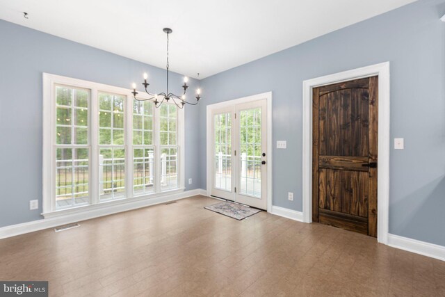 unfurnished dining area featuring a chandelier, baseboards, and french doors