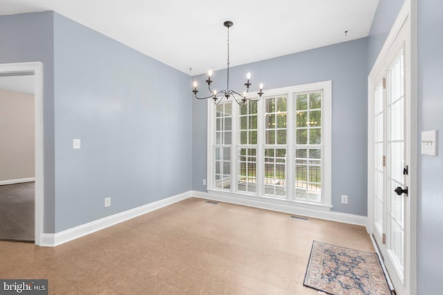 unfurnished dining area with a chandelier, baseboards, and tile patterned floors