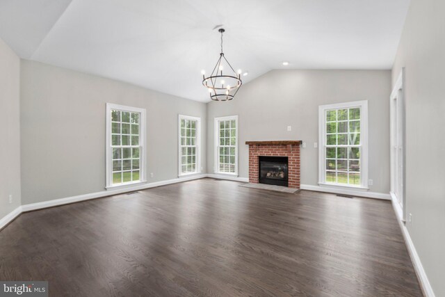 unfurnished living room with healthy amount of natural light, a chandelier, a brick fireplace, dark wood-type flooring, and high vaulted ceiling