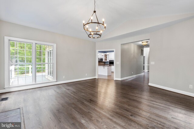 spare room with a chandelier, vaulted ceiling, dark wood-type flooring, and baseboards