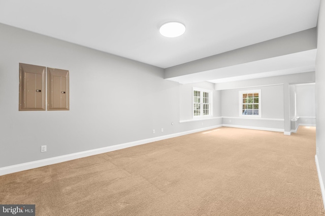unfurnished room featuring light carpet, baseboards, and electric panel