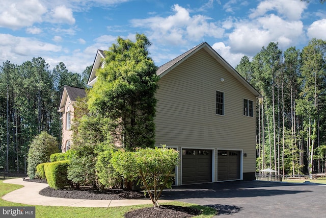 view of side of home with a garage and asphalt driveway