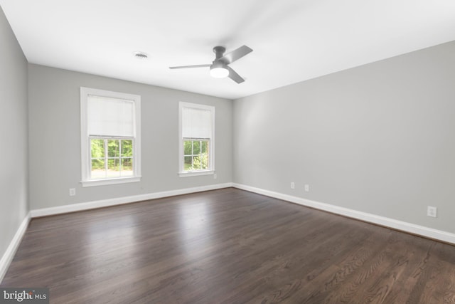 empty room with baseboards, dark wood-type flooring, and a ceiling fan