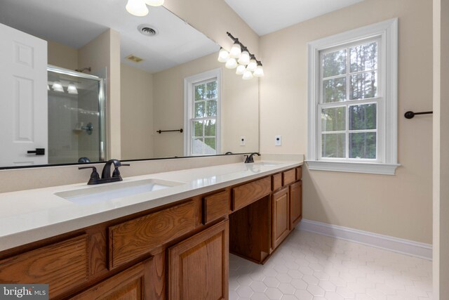 bathroom with a stall shower, double vanity, baseboards, and tile patterned floors