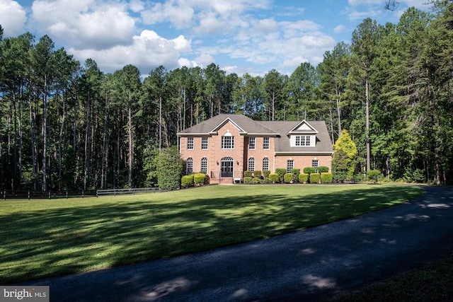 georgian-style home featuring brick siding and a wooded view