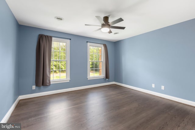 spare room with baseboards, a ceiling fan, and dark wood-style flooring